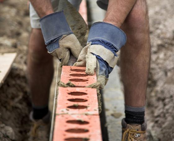construction site with a large red crane lifting materials for building a structure under a clear blue sky ten construction elements visible